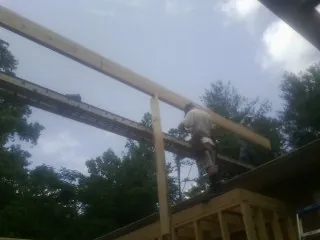 Carpenter setting a ridge beam over a new addition frame — Ice Dam Removal by Roofing Brothers in Malcolm
