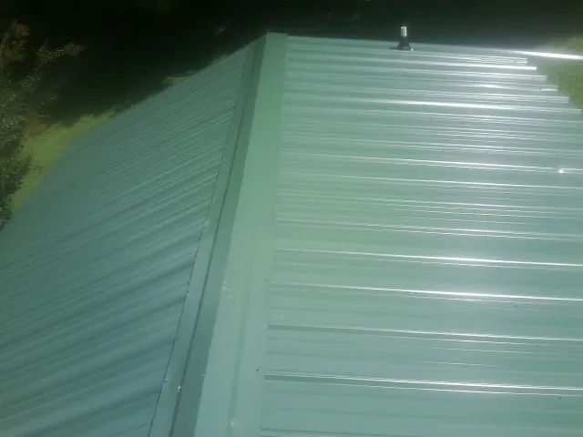 New green metal panels meeting at the ridge of a roof — Flat Roof Repair work by our crew in Malcolm