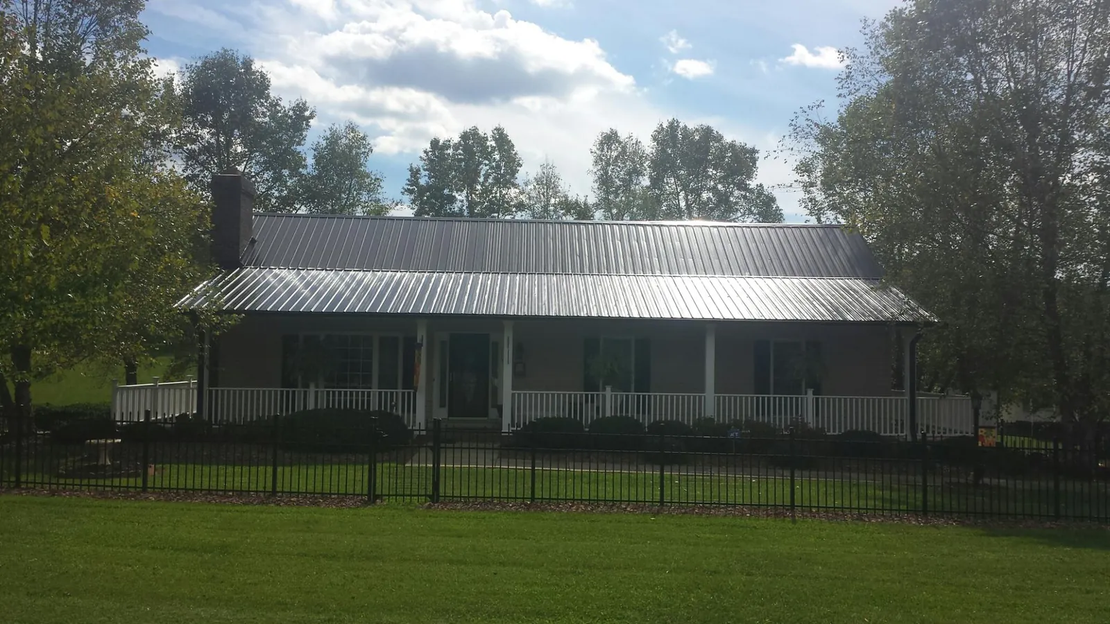 Gray metal roof on a brick ranch with a full width front porch — Gutter Guard Installation work by our crew in Malcolm